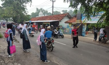 Bhabinkamtibmas Polsek Telagasari Bantu Siswa Menyebrang Saat Gatur Pagi 